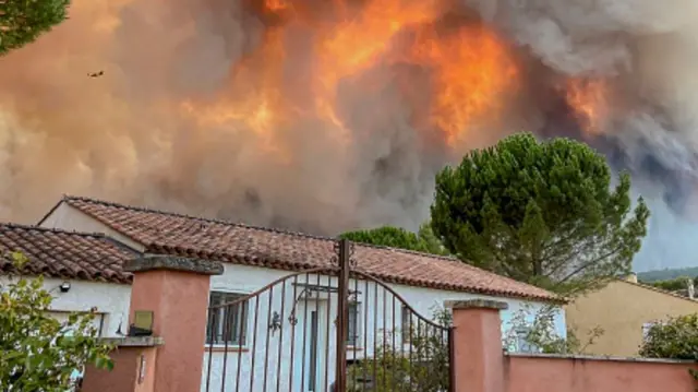 Bystanders watch di smoke and flames from one wildfire on July 21, 2026 in Cotignac, France.