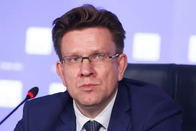 Портрет генерального директора "Эксмо" Евгения Капьева на пресс-конференции в 2026 году. Снимок крупным планом: Капьев в очках и синем костюме. 