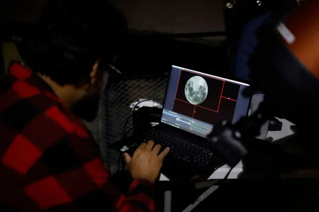 Scientists dey look di Moon wey dey displayed on a screen for di Foster Observatory for Santiago