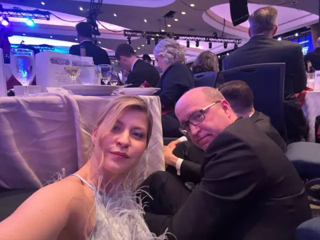 Селфі Стефанішиної: у великому банкетному залі вона і двоє чоловіків сидять на підлозі між стільцями й столами.