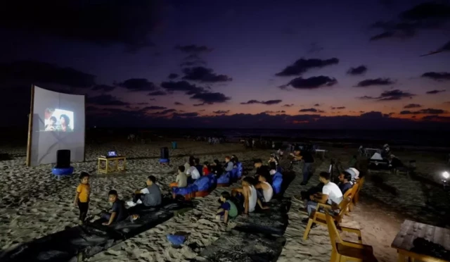 فلسطينيون يتابعون شاشة عرض سينمائية 