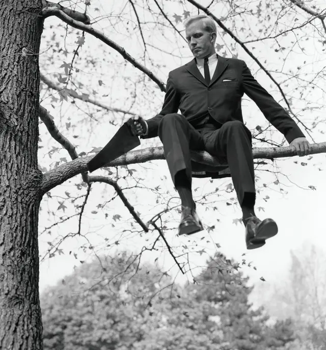 Hombre serruchando la rama de árbol en la que está sentado