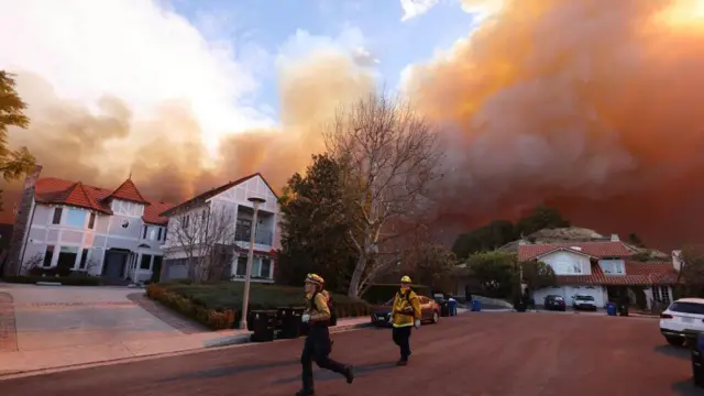 los angeles'taki yangından binaların üzerini sarmış dumanlar ve yoldaki itfaiyeciler