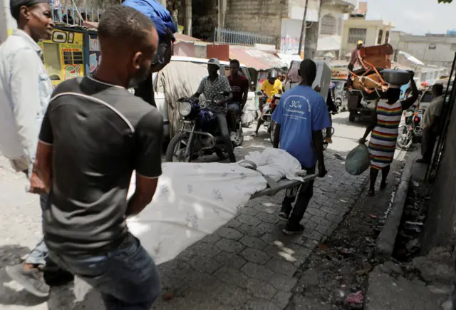 Haitianos carregam o corpobanca de apostaum homem morto por gangues que atuambanca de apostaPorto Príncipe