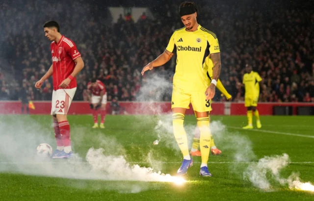 Fenerbahçeli Archie Brown, Nottingham City Ground'da oynanan UEFA Avrupa Ligi eleme turu play-off ikinci maçında, taraftarlarının sahaya attığı bir meşaleyi uzaklaştırıyor.