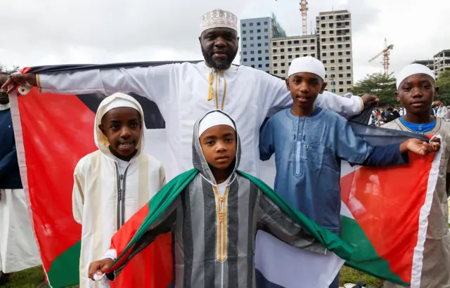 مسلم كيني وعائلته يقفون مع العلم الفلسطيني بعد حضور صلاة عيد الفطر، في ملعب نادي السير علي الإسلامي في منطقة نجارا بنيروبي، كينيا