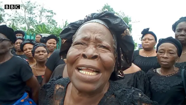 Ụfọdụ ụmụnwaanyị Uzzi ji akwa na bata ogige ụlọikpe ukwu Ụmụahịa maka okwu ala ha.