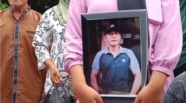 Seorang perempuan dari keluarga korban sedang membawa bingkai foto salah satu korban sipil yang meninggal dalam ledakan amunisi di Garut.