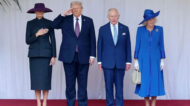 First Lady Melania Trump wearing black outfit wit hand for her chest, U.S. President Donald Trump salute, King Charles III and Queen Camilla in blue dress standing and looking straight during di State visit by di US president for Windsor Castle on September 17, 2025 for Windsor, England.