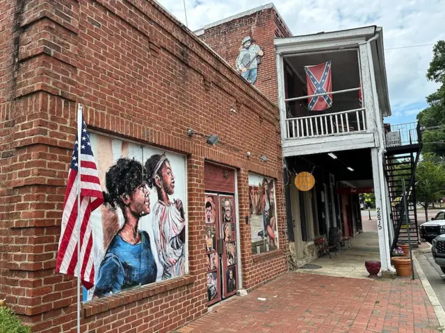 Una calle de la ciudad de Kennesaw, donde están colgadas una bandera estadounidense y una bandera confederada.