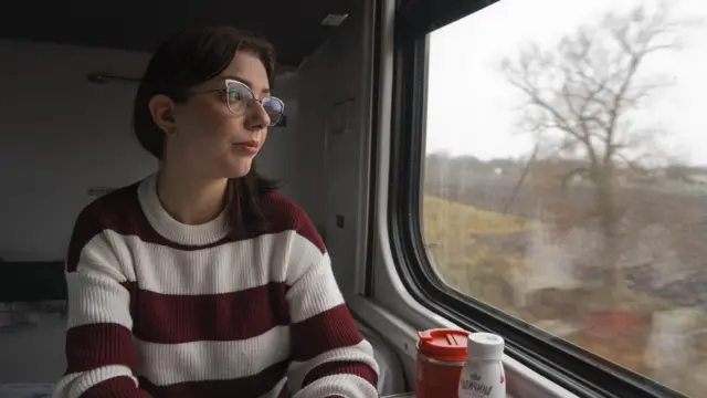 Дівчина в окулярах дивиться у вікно поїзда