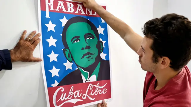 A picture of a man putting up a poster that showed a cartoon Barack Obama with the words "Habana - Cuba Libre" marking the 10th anniversary of a historic attempt at reconciliation between the two countries in 2014.