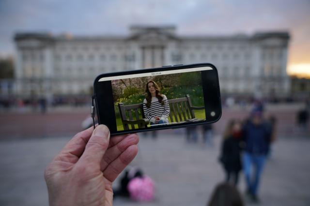 Pessoa assiste a discurso de Kate Middleton pelo celular
