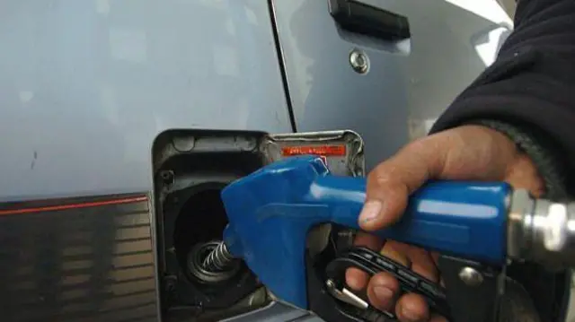 فردی در حال واریزکردن تیل به موترش.