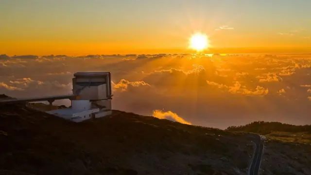 La instalación, en una montaña, con nubes, al atardecer