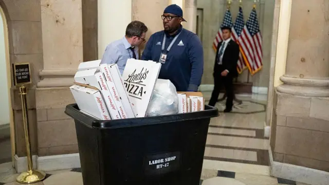 Рабочий выкатывает из кабинета спикера Палаты представителей Майка Джонсона контейнер, полный пустых коробок из-под пиццы