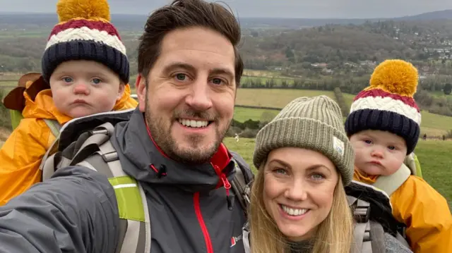 Shaun caminha com a companheira e os dois filhos pequenos, com gorros de pompom iguais

