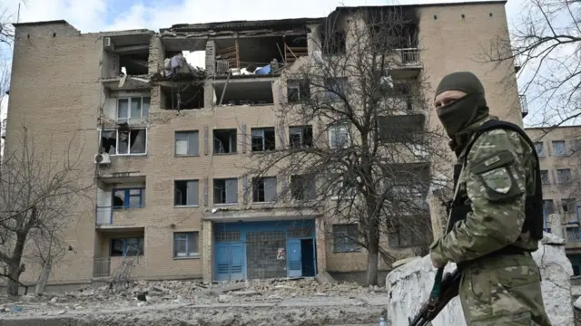 Боєць біля зруйнованої будівлі