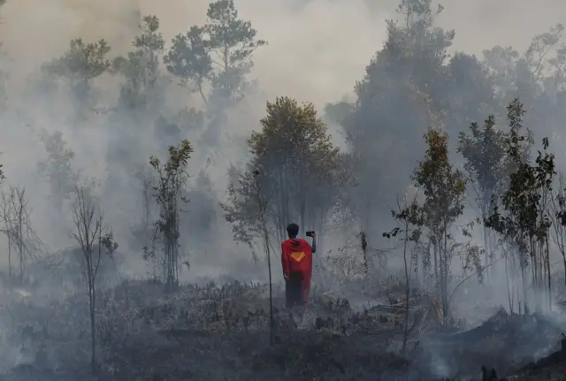 Rudiyansah, 16, memakai kostum Superman saat memeriksa dan memadamkan kebakaran hutan dan lahan di Palangka Raya, Kalimantan Tengah, pada 14 Agustus 2026.