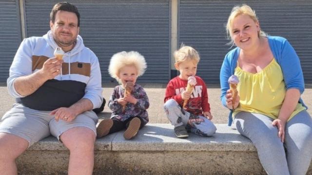 Quatro membros da família sorrindo em banco e tomando sorvetes 