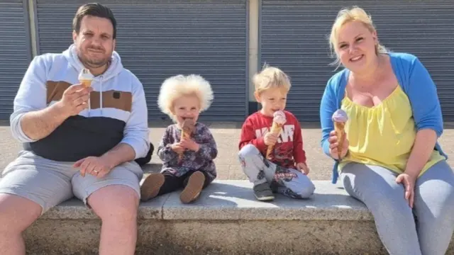 Quatro membros da família sorrindoshow ball bingo grátisbanco e tomando sorvetes 