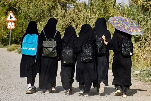 چند دختر که لباس سیاه مکتب بر تن دارند