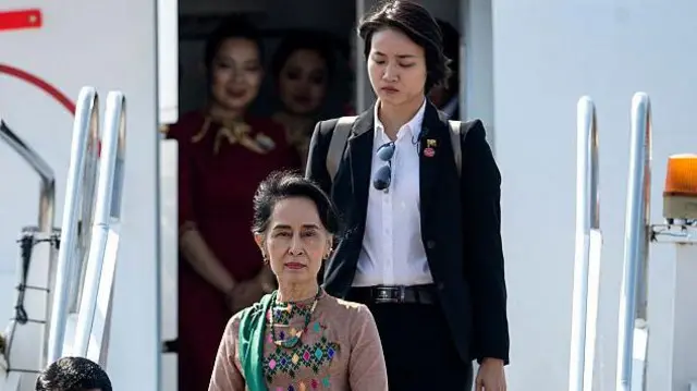 ဒေါ်အောင်ဆန်းစုကြည်နဲ့ ကိုယ်ရံတော်ချယ်ရီထက်ကို လေယာဥ်ပေါ်က ဆင်းအလာမှာတွေ့ရပါတယ်။ ဒေါ်အောင်ဆန်းစုကြည်က မြန်မာဝတ်စုံကို ဝတ်ဆင်ထားပြီး ကိုယ်ရံတော်ချယ်ရီထက်ကတော့ အနောက်တိုင်းဝတ်စုံနဲ့ပါ။