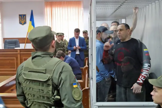 Các cựu binh sĩ của đơn vị cảnh sát tuần tra đặc nhiệm khét tiếng Tornado, những người đang phải đối mặt với các cáo buộc phạm những tội ác nghiêm trọng, đứng trong buồng kính tại phiên điều trần chuẩn bị ở Tòa án Quận Shevchenkivskyi, thủ đô Kyiv của Ukraine, ngày 6/6/2019.