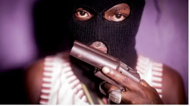 Ẹnikan fi àwọ̀n dudu bo ori ati oju rẹ, o yọ abala oju meji silẹ lasan o si mu ibọn dani