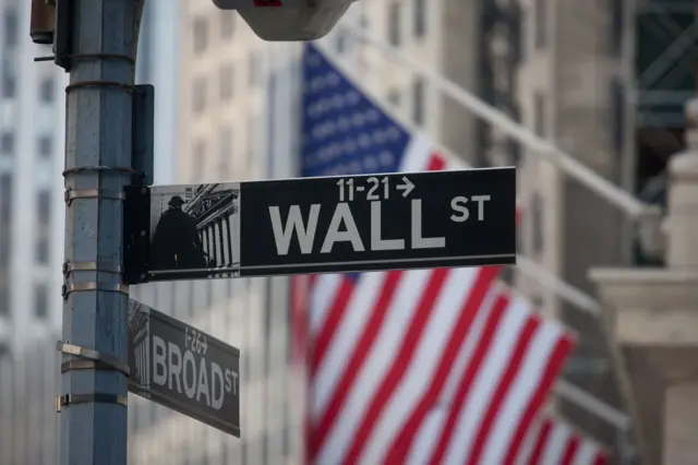 Placa da rua de Wall Street com a bandeira dos EUA no fundo 