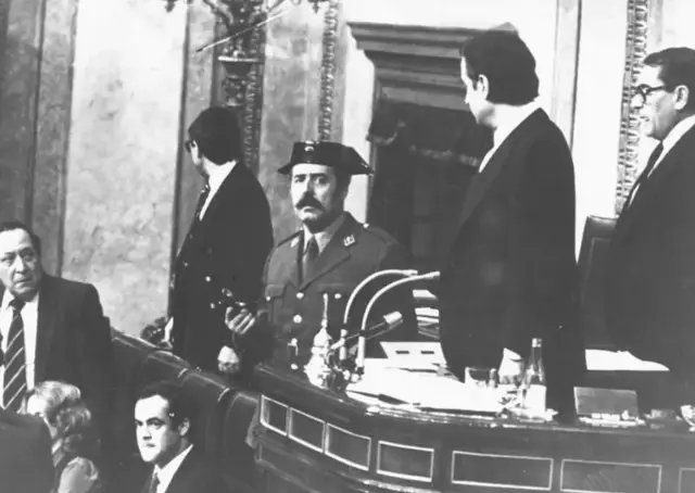 ستوان تجرو رهبری کنگره اسپانیا را به دست می‌گیرد، او در پارلمان با اسلحه ایستاده و تعدادی از نمایندگان نیز ایستاده‌اند به نظر نگران می‌آیند