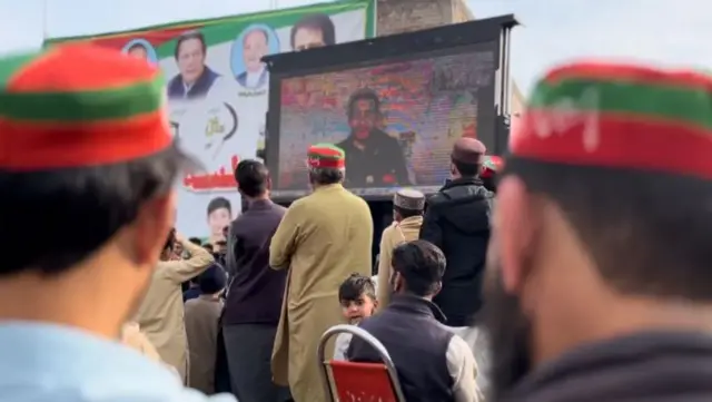 बड़े पर्दे पर चुनाव प्रचार करता एक पीटीआई समर्थित उम्मीदवार 