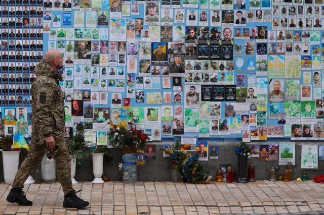 Soldado passa pelo muro memorial aos soldados mortos em Kiev, 4 de fevereiro de 2024