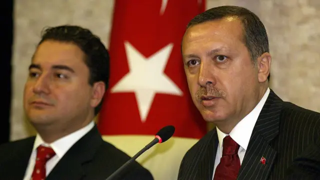 16 Eylül 2004'te, dönemin Ekonomiden Sorumlu Devlet Bakanı Ali Babacan ve Başbakan Recep Tayyip Erdoğan, Türk Lirası'ndan altı sıfırın atılmasıyla ilgili basın açıklaması yapıyor. Arkada bir Türk bayrağı gözüküyor.