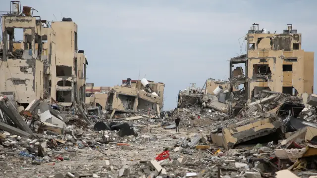 شاب يسير بين أنقاض مبانٍ مدمرة في رفح على وقع الهجوم الإسرائيلي بعد دخول وقف إطلاق النار حيز التنفيذ 