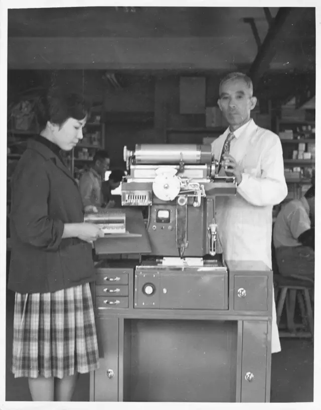 फोटोटाईपसेटिंग मशीन सोबत नोबुओ मोरीसावा (उजवीकडे)