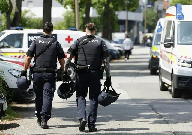 Graz'da silahlı saldırı sonrası sırtı dönük iki polis ve polis araçları