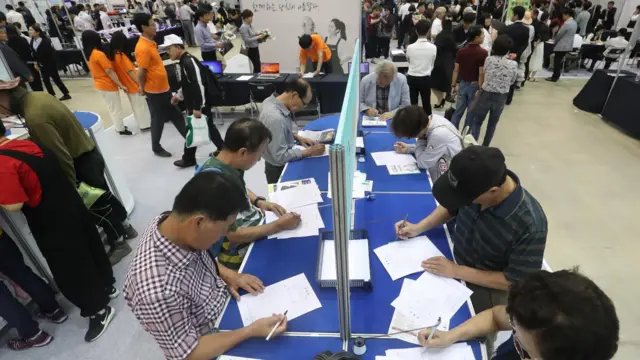 시니어 구직자들이 일자리 행사장에서 이력서를 작성하고 있다