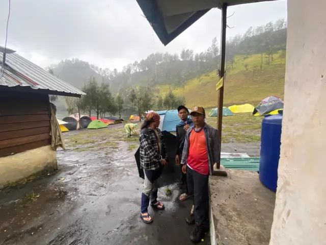 Tiga pria sedang berada di area perkemahan.