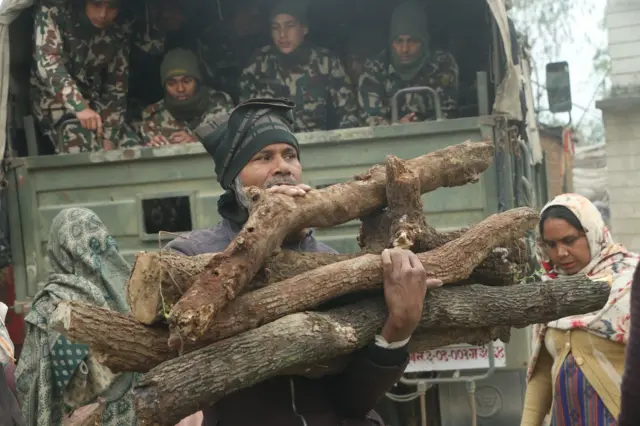 बाँकेको नेपालगन्जको ग्रामीण क्षेत्रमा सेनाले वितरण गरेको दाउरा लिँदै स्थानीय बासिन्दाहरू