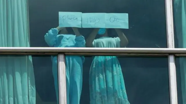 Two young migrants, who have been deported from the US, stand at a hotel window in Panama City and ask for help