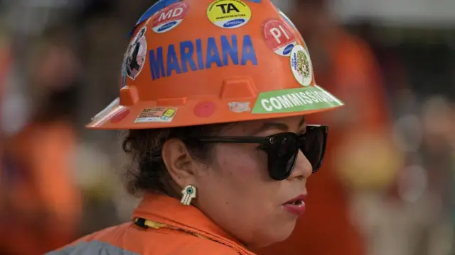 Una trabajadora de Pemex con el mono naranja y un casco del mismo color.