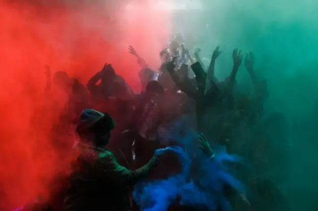 Crowds of smiling people are covered in multicoloured powder.
