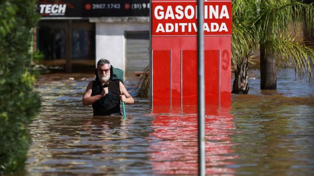 Homem caminha em área inundada