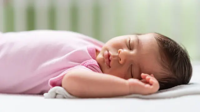 Bebê dormindo de costas em um berço