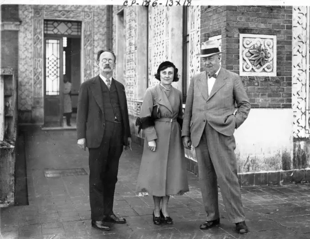 Foto em preta e branco que mostra Adolfo Lutz em pé usando terno e gravata ao lado da filha Bertha Luz e um outro homem