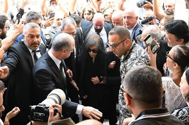 فيروز وسط حشد من المعزين برحيل زياد الرحباني وعدسات الكاميرات تحيط بها.