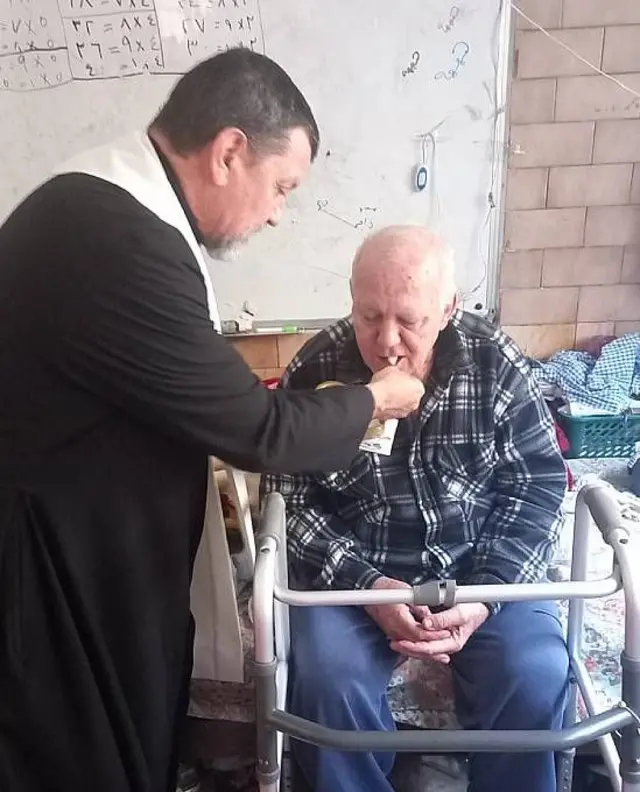 Padre argentino Carlos Ferrero dando la hostia a un hombre mayor que tiene dificultades para caminar