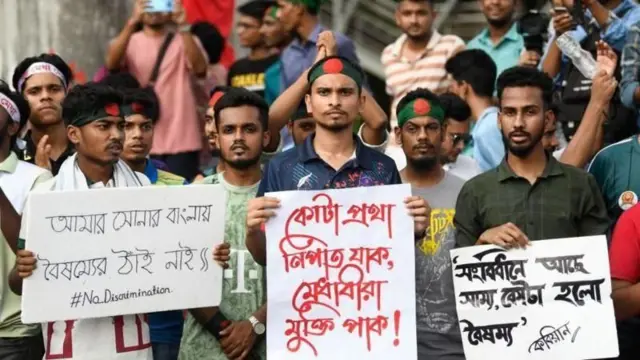 জুলাই আন্দোলনের সময় কোটাপ্রথা বিরোধী স্লোগান লেখা প্ল্যাকার্ড হাতে দাঁড়িয়ে আছেন কয়েকজন আন্দোলনকারী