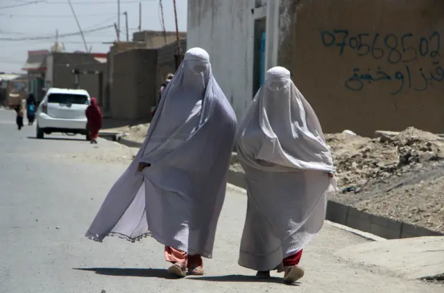 Burqa-clad Afghan women walk on a road in Kandahar, Afghanistan, 22 August 2024